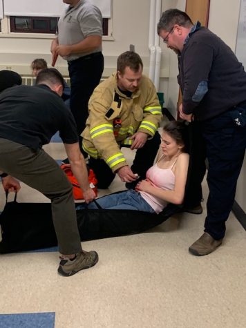  Hamilton-Wenham police and firemen practice administering aid to student volunteers.