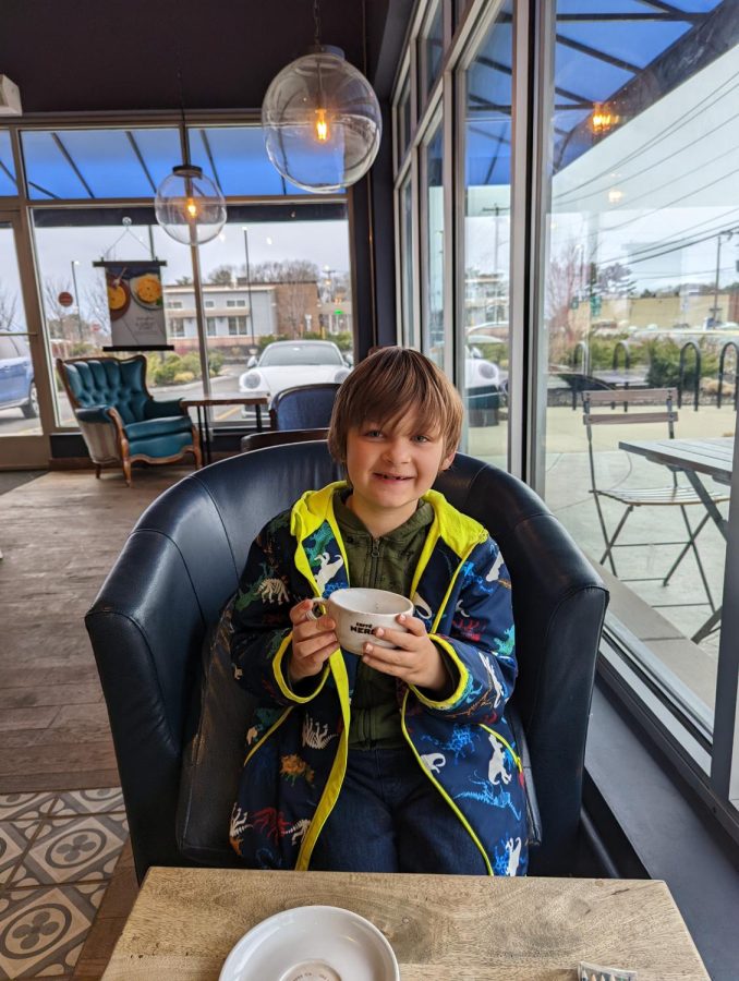 Child enjoying the cafe atmosphere while drinking hot cocoa, which has a minimal amount of caffeine. 