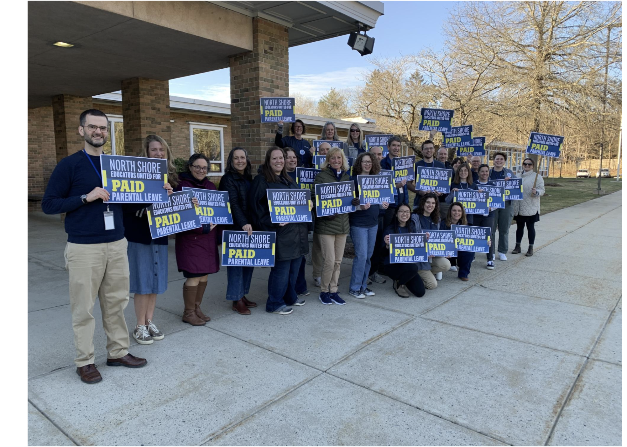 Teachers at Hamiton Wenham Regional High School stand outside the school to voice their support for paid parental leave. 