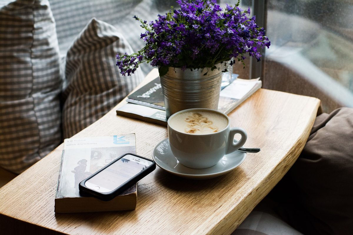 A phone sits on top of a book surrounded by pleasant table arrangements and background. 