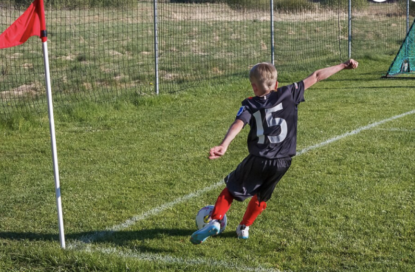A boy taking a corner kick during a friendly little league soccer game with mixed teams the north soccer training field in Brastad arena, Brastad, Lysekil Municipality, Sweden. One of the teams is the local SAIS.